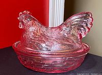 Pink glass nesting chicken dish showing detailed chicken lid and basket-shaped base with textured pattern.
