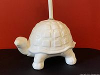 Side view of white ceramic turtle lamp base showing detailed turtle shape and glossy finish