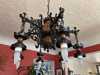 Chandelier installed and hanging from ceiling, showing six candle-shaped bulbs and ornate metal and wood design.