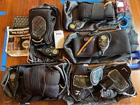 Overview of multiple Flex Belt muscle toning units and accessories on wood table, showing digital controllers and elastic straps.