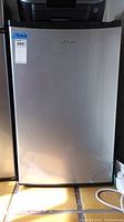 Full front view of the Whirlpool mini fridge showing stainless steel door and overall shape.