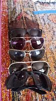 Five pairs of sunglasses laid out on a patterned carpet.