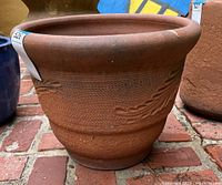 Side angle view of the large terra cotta planter pot sitting on a brick surface.