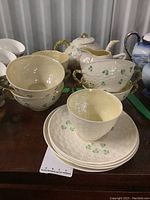 Overview of the ten pieces Belleek china set with stacked soup bowls, tea cup, and saucers showing the green shamrock decoration