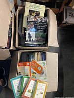 Two open boxes full of assorted books including children's books with colorful covers and more serious horse-themed and reference books.