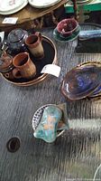 Photo showing copper tray holding two teapots and two mugs with ceramic plates around them, highlighting various ceramic styles and glaze colors.