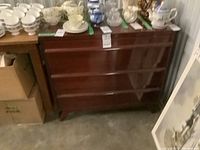 Gibbard three drawer dresser in storage area with visible scuffs on exterior.