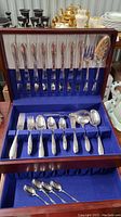 Full view of the wooden flatware case lined with blue velvet showing all flatware pieces arranged in two levels.