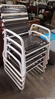 Stacked set of four vintage lawn chairs from an angle showing the seats and frames.