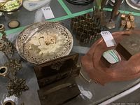 Overview of copper tray, brass napkin rings, trinket boxes, and candle holders on a table