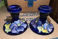 Pair of Moorcroft ceramic candle holders with blue background and hand-painted pastel floral Anemone decoration.