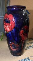 Side view showing red poppy decoration on dark blue glaze.