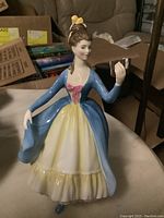 Front view of the Royal Doulton Leading Lady HN2269 porcelain figurine showing the woman in a long blue dress with yellow and pink accents holding a book.