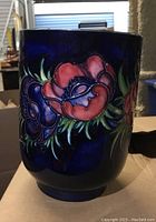 Front oblique view of Moorcroft vase showing red poppy design on blue background
