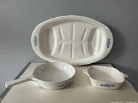 Full view of the set showing the oblong dish, saucepan, and petite pan with their blue cornflower designs.