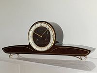 Front view of wooden mantle clock showing curved design and clock face.