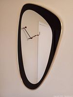 Mirror hung on wall showing full amoeba shape and frame