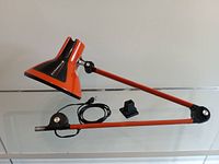 Photo of vintage orange architect lamp with articulated arm fully extended showing the shade, arm, mounting bracket and power cord.