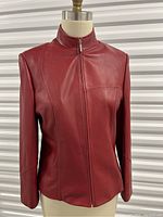 Front view of red leather moto jacket on mannequin showing zipper closed and overall jacket design.