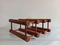 Side angle view of vintage teak wine rack made with cylindrical rods showing craftsmanship and brand stamping on end