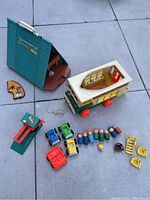Wide shot of the complete vintage Fisher Price Play Family camper, A-Frame house, people figures, cars, car lift, and accessories.