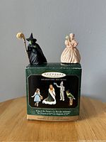 Wicked Witch and Glinda mini ornaments on a Hallmark Keepsake box showing Wizard of Oz characters for scale