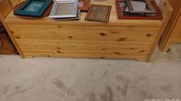 Front view of wooden storage bench with picture frames placed on top (not included)