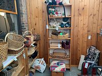 Front view of wood bookcase with shelves holding various stuffed animals and woven baskets around it