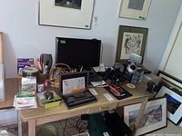 Wide shot of the desk with all items clearly visible including monitor, keyboard, pens, calligraphy set, binoculars, and various office supplies.