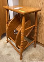 Side angle view of the oak step stool showing the turned legs and assembled drop-down steps folded out.