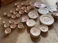 Full view of Royal Doulton Grantman china set including plates, saucers, bowls, cups, teapot, platter, and sugar bowl, arranged on carpet.