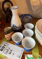 Sake set with carafe and four cups positioned in front of stacked plates.