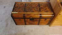 Front view of wood trunk showing metal straps and lock