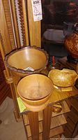 Three wood bowls arranged on a wooden surface, showing size and finish differences; one with natural edge bark.