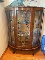 Full view of antique wooden display cabinet showing curved front glass panels and wooden frame with visible wood grain.