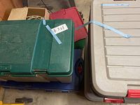Four stacked plastic storage bins of various colors containing Christmas lights and extension cords.