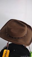 Brown felt cowboy hat shown from angled front view highlighting the crown and brim with decorative band.