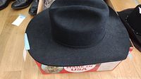 Close-up front angled view of black felt cowboy hat with visible silver buckles and wide brim in good condition.