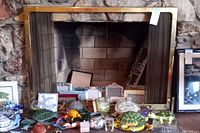 Full frontal view of brass fireplace screen with mesh curtain covering a stone fireplace opening. Various unrelated items in foreground and to sides.