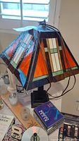 Front and side view of the stained glass table lamp showing the geometric pattern on the shade and black metal base.