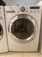 Front view of white LG front load electric dryer with chrome-trimmed door