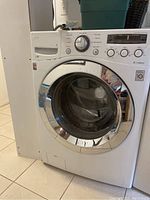 Front view of white LG front load washing machine with chrome door trim
