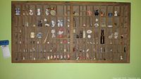 Full view of wooden display case containing various miniature collectibles in small compartments.