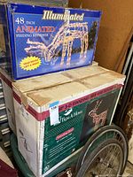 Boxes for two outdoor lighted reindeer decorations: one for a 48-inch illuminated animated feeding reindeer with head movement, and another for a 49-inch 3D standing deer wire silhouette with 300 lights.