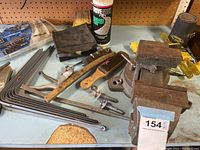 Photo showing metal bench vise, hammer, riveter, hex keys, hand brush, Degr-Solv cleaning spray, and black pouch laid out on workbench