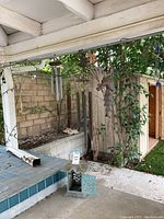 Overall photo showing metal garden lantern on ground and hanging wind chimes under patio roof.