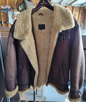 Front view of vintage US Army Air Force Type B-3 sheepskin leather aviator jacket with shearling collar and interior lining, visible brand and contract info on black label inside.