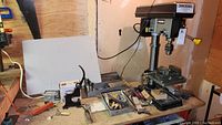 Complete view of the workbench with drill press, drill bits, hand tools, and hardware.