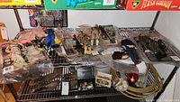 Six GI Joe military action figures laid out on metal shelf with accessories and packaging