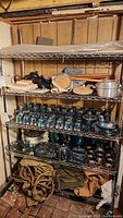 Metal shelves holding two rows of vintage military equipment and camping gear, showing items and general shelf contents.